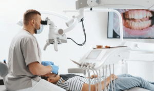 Dentist examining patient's teeth using surgical microscope in modern dental clinic operatory.