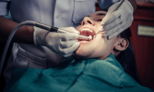 Dentist examining patient's teeth and gums during dental checkup procedure.