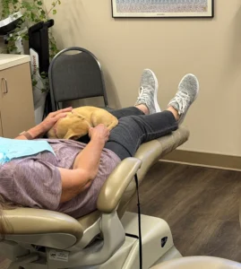 Person reclining in dental chair during examination at Roots & Gums dental office.